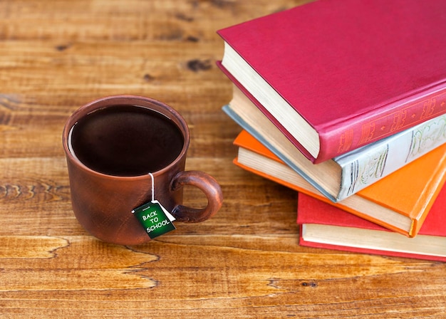 a mug with tea and an inscription stands on a table with a stack of books