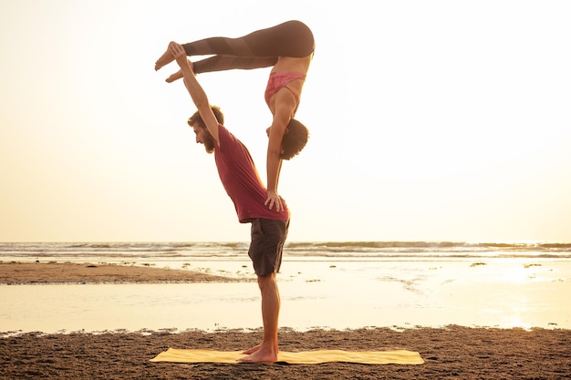 Muladhara swadhisthana manipula tantra yoga on the beach man and woman meditates sitting on the sand by the sea at sunset romantic Valentine's Daycouple practicing yoga steam