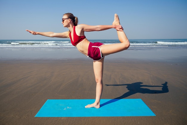 Muladhara swadhisthana manipula tantra yoga on the beach woman meditates sitting on the sand yoga mat by the sea at summer morning female model sitting on a twine and doing stretching