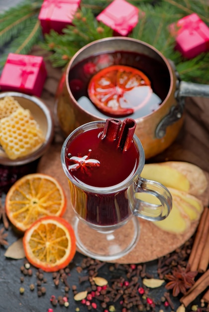 Mulled wine, blue pine tree branch and spices on wooden background.