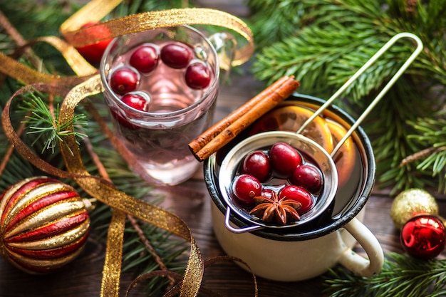 Mulled wine in metall mug with berries cinnamon sticks and star anise on brown wood table