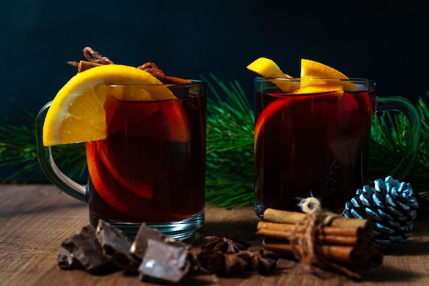 Mulled wine with aromatic spices and orange pieces on a wooden background