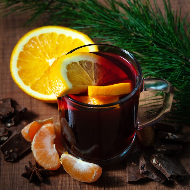 Mulled wine with aromatic spices on a wooden background