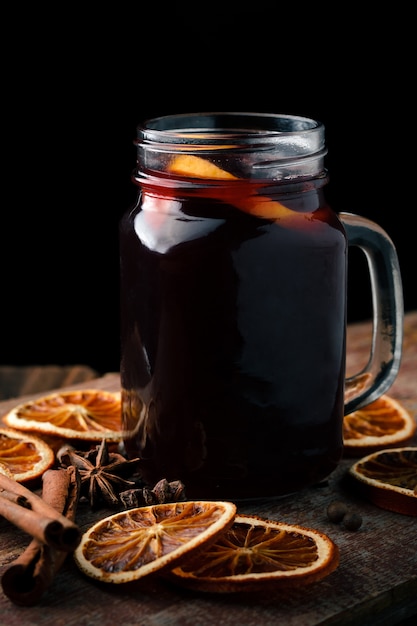 Mulled wine with oranges, cinnamon sticks and anise on a wooden table.