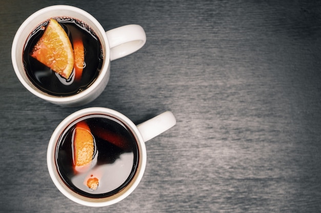 Mulled wine with slices of orange in the white cups on wood table