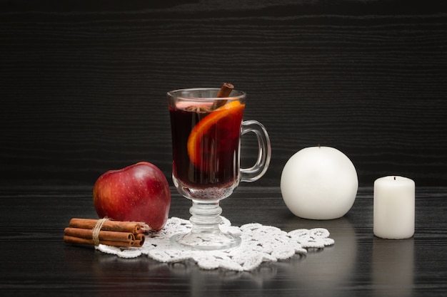 Mulled wine with spices. Candles, cinnamon sticks and apple.