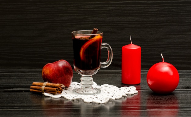 Mulled wine with spices on a lace napkin and red candles