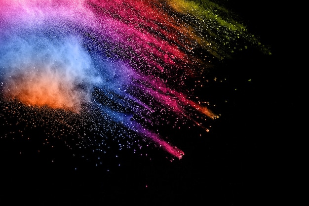 Multi color powder explosion on black background. Launched colorful dust  particles splash