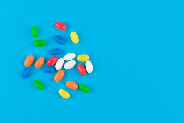 Multi colored candies on a blue background. Tasty colorful candies on blue background. Flat lay.