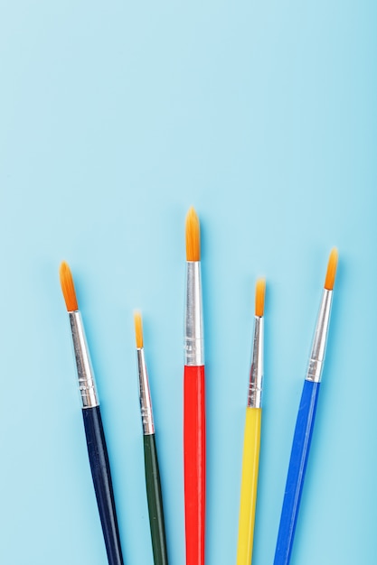 Multi-colored paint Brushes on a blue background.