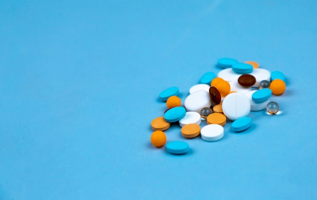 Multi-colored pills on a blue background close-up,