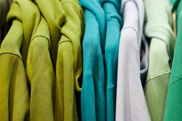 multi-colored sweatshirts on hangers in the store. Bright colorful sweatshirts hang in a store