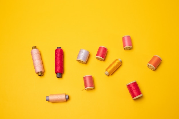 Multi-colored thread spools or sewing accessories on a yellow background.