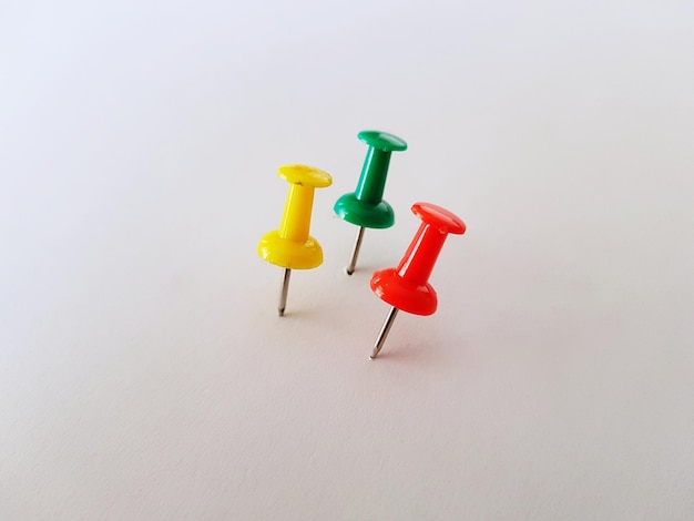 Photo multi colored thumbtacks over white background