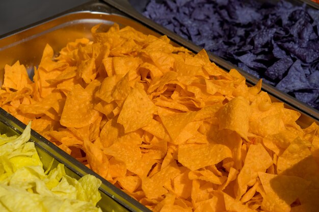 Photo multi colored tortilla chips in trays on the showcase. street food festival. selective focus.