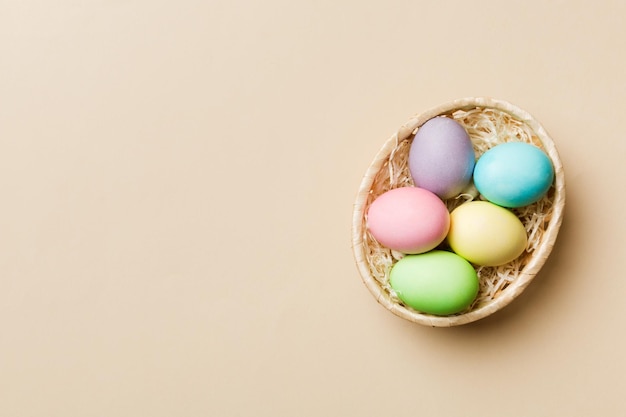 Multi colors Easter eggs in the woven basket on colored background Pastel color Easter eggs holiday concept with copy space