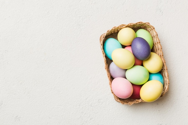 Multi colors Easter eggs in the woven basket on colored background Pastel color Easter eggs holiday concept with copy space