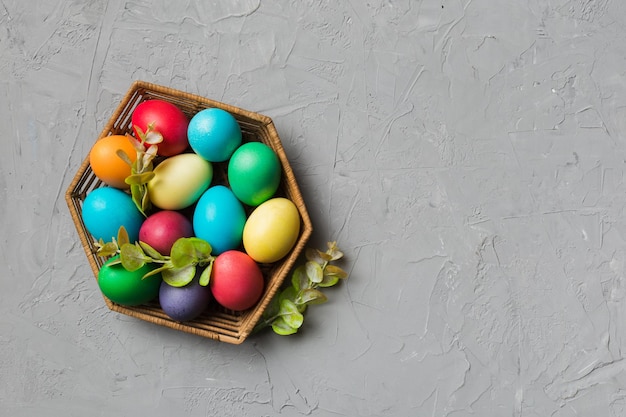 Multi colors Easter eggs in the woven basket on colored background Pastel color Easter eggs holiday concept with copy space