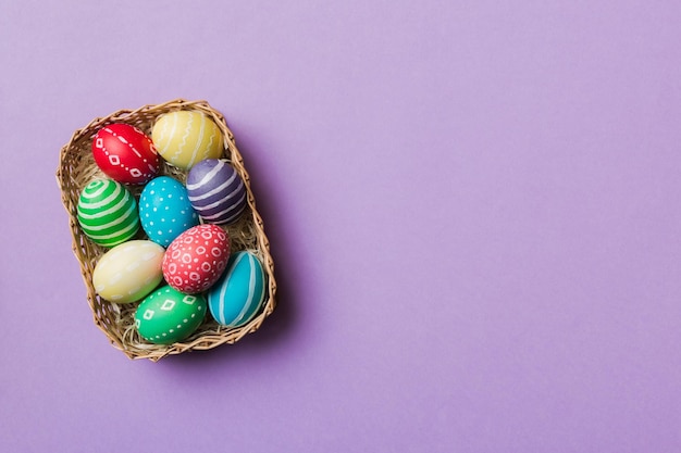 Multi colors Easter eggs in the woven basket on colored background Pastel color Easter eggs holiday concept with copy space