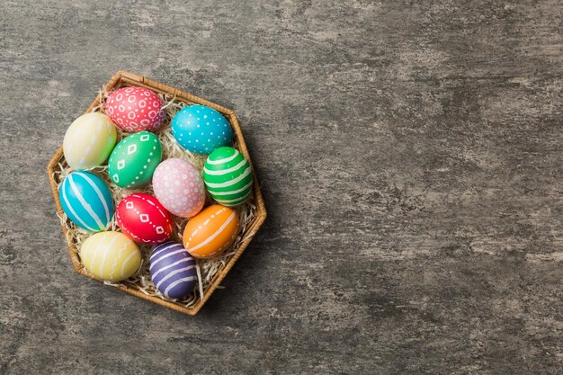 Multi colors Easter eggs in the woven basket on colored background Pastel color Easter eggs holiday concept with copy space