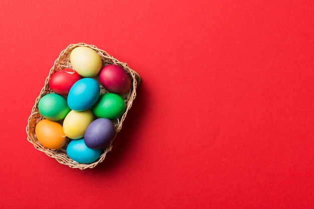 Multi colors Easter eggs in the woven basket on colored background Pastel color Easter eggs holiday concept with copy space