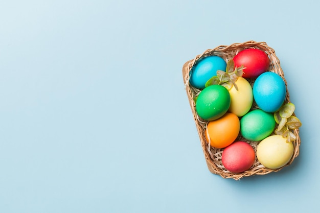 Multi colors Easter eggs in the woven basket on colored background Pastel color Easter eggs holiday concept with copy space