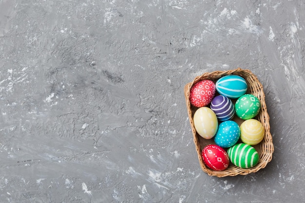 Multi colors Easter eggs in the woven basket on colored background Pastel color Easter eggs holiday concept with copy space