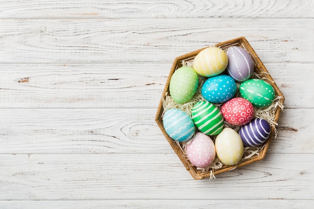 Multi colors Easter eggs in the woven basket on colored background Pastel color Easter eggs holiday concept with copy space