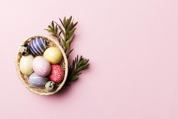 Multi colors Easter eggs in the woven basket on colored background Pastel color Easter eggs holiday concept with copy space