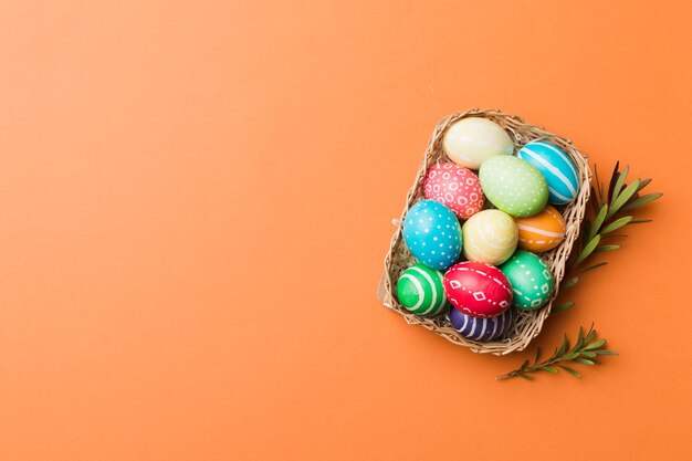 Multi colors Easter eggs in the woven basket on colored background Pastel color Easter eggs holiday concept with copy space