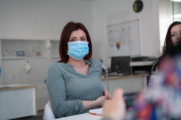 multi-ethnic businesspeople team working in bright modern office wearing protecive medical mask during coronavirus outbreak new normal concept in business