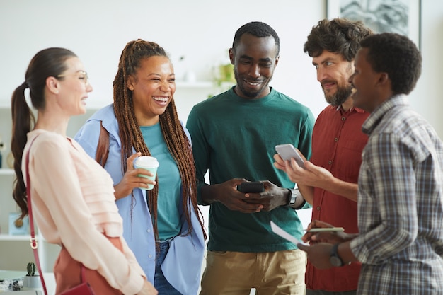 Photo multi-ethnic group of people dressed in casual wear and laughing cheerfully while chatting in office