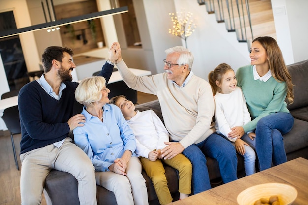 Multi generation family sitting together on the sofa at modern home and watching TV