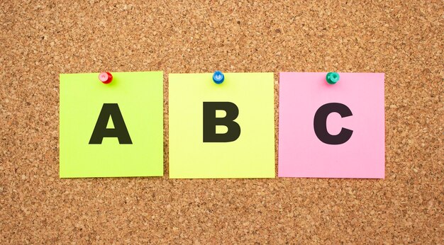 Multicolor notes with letters pinned on a cork notice board.