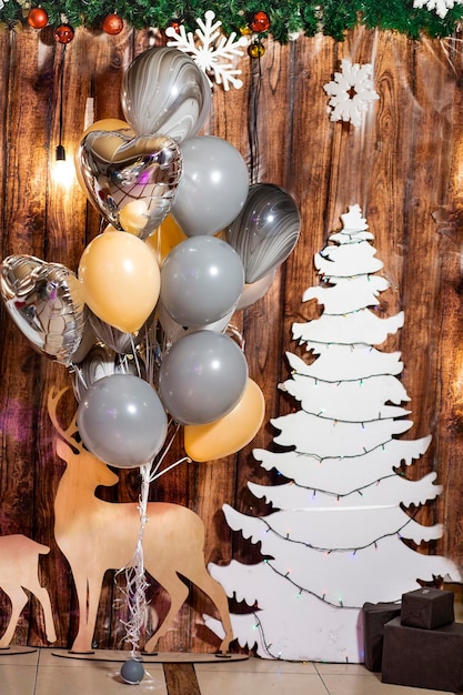 Multicolored balloons a white Christmas tree with garlands snowflakes deer on a wooden background