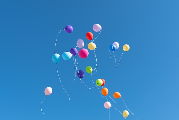 Multicolored balls released into the blue sky 