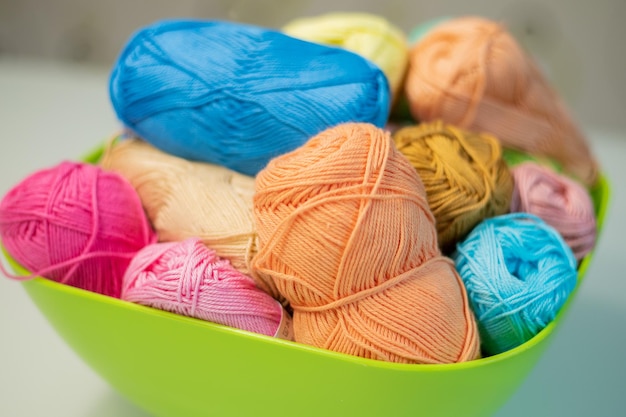 Multicolored bright yarn lies in a box on a white table selective focus