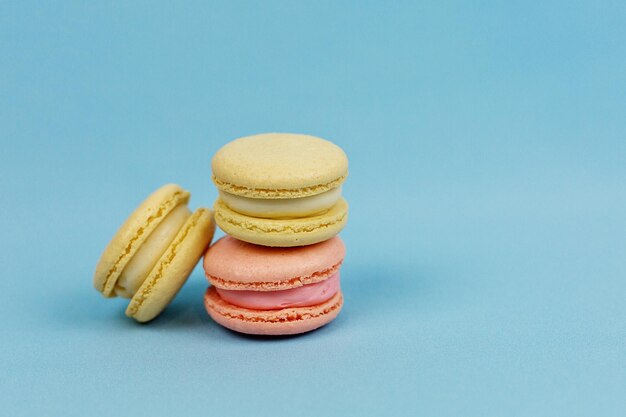 Multicolored cakes on a blue background with a space to copy Orange macaroons Sweets