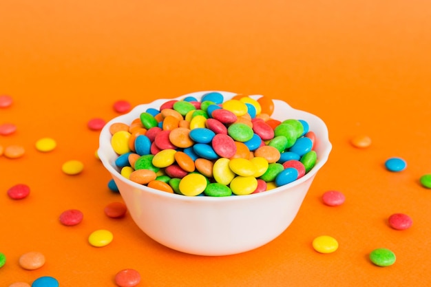 Multicolored candies in a bowl on a colored background birthday and holiday concept Top view with copy space