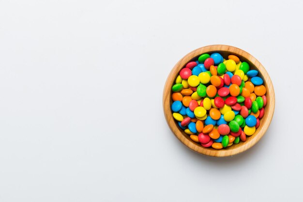 Multicolored candies in a bowl on a colored background birthday and holiday concept Top view with copy space