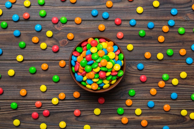 Multicolored candies in a bowl on a colored background birthday and holiday concept Top view with copy space