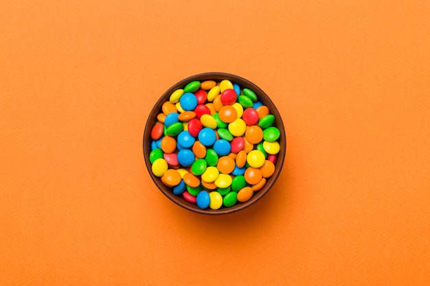 Multicolored candies in a bowl on a colored background birthday and holiday concept Top view with copy space