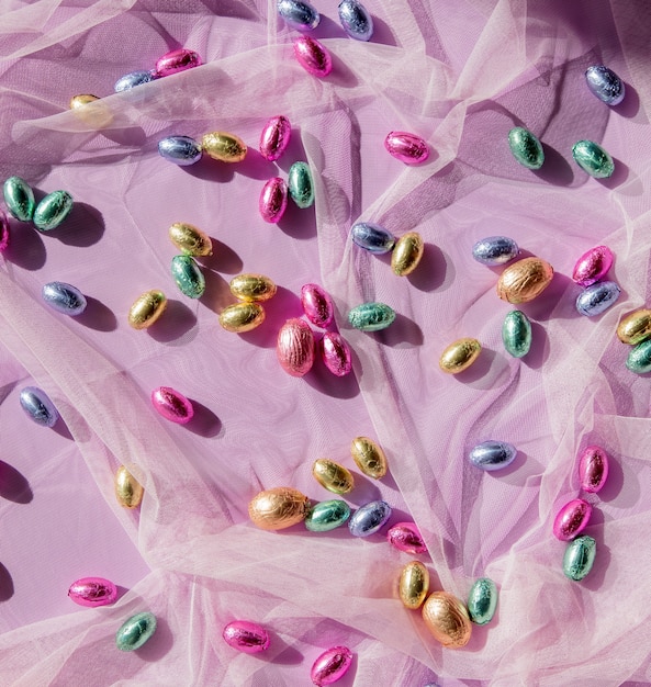 Multicolored chocolate eggs on pink tulle. Above view