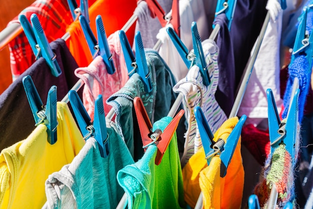 Multicolored clothes hang attached to clothespins and dry after washing closeup