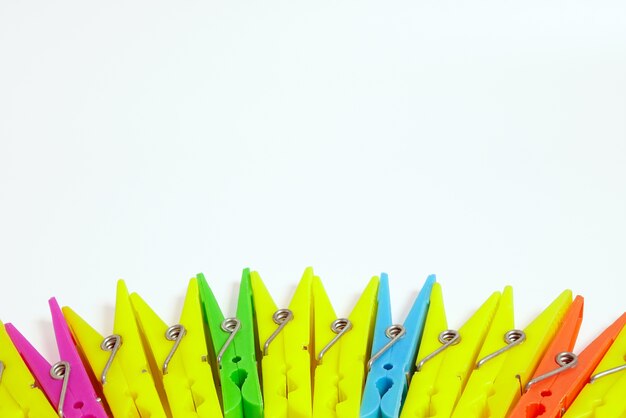 Multicolored clothespins on white background with copy space top view