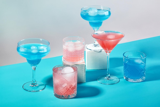 Multicolored cocktails in glasses of different shapes on colored backgrounds with hard shadows