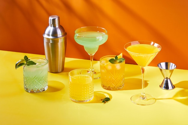 Multicolored cocktails in glasses of different shapes on colored backgrounds with hard shadows