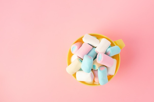 Multicolored colored vibrant marshmallows in a bowl on a pink background