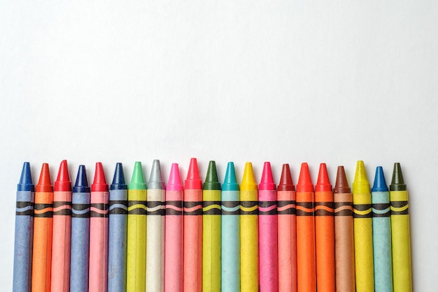 Multicolored crayons lined up on white background