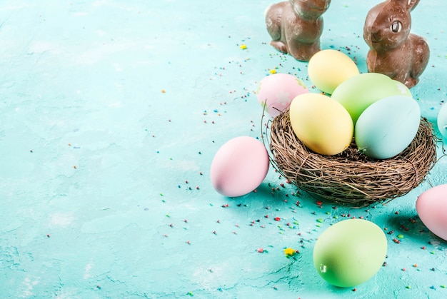 Multicolored Easter eggs with decorative bird's nest and sugar sprinkles on a light blue ,